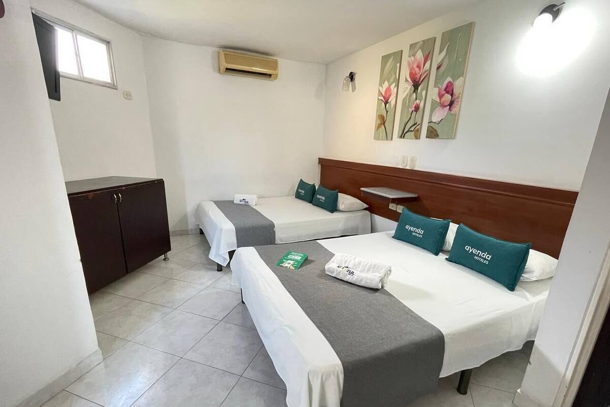 A hotel room with two beds, a wardrobe, and a window.
