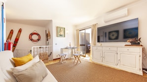 Un salon comprenant un canapé, une table basse, un téléviseur et un coin repas avec des chaises et une table.