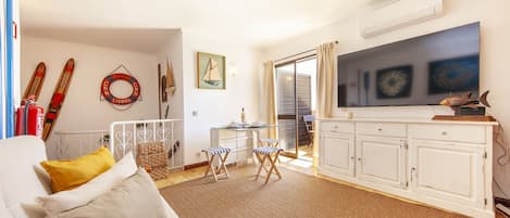 Una sala de estar con sofá, mesa de centro, televisor y un área de comedor con sillas y mesa.