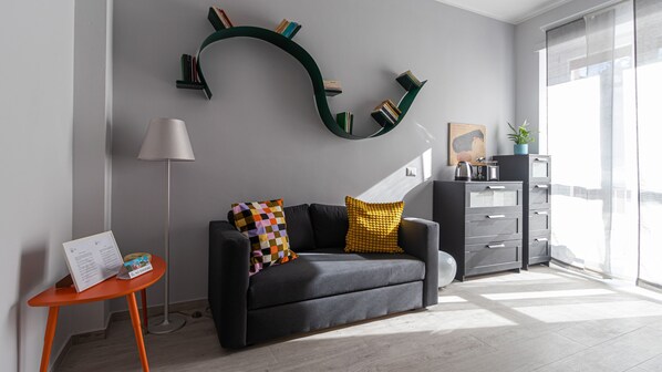 A modern living room with a sofa, a small table, a lamp, and a bookshelf against the wall. - Italianway Comfort - Copernico 47 B (Milan)