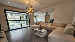 A modern living room with a large sectional sofa, a white coffee table, and a unique chandelier.