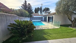 A modern outdoor pool area with a clear view of the pool, surrounded by a well-maintained lawn and a concrete wall.