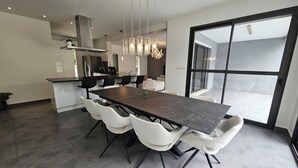 A modern kitchen with a large island, dark countertops, and white chairs.