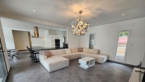 A modern living room with a sectional sofa, a coffee table, and a unique chandelier.