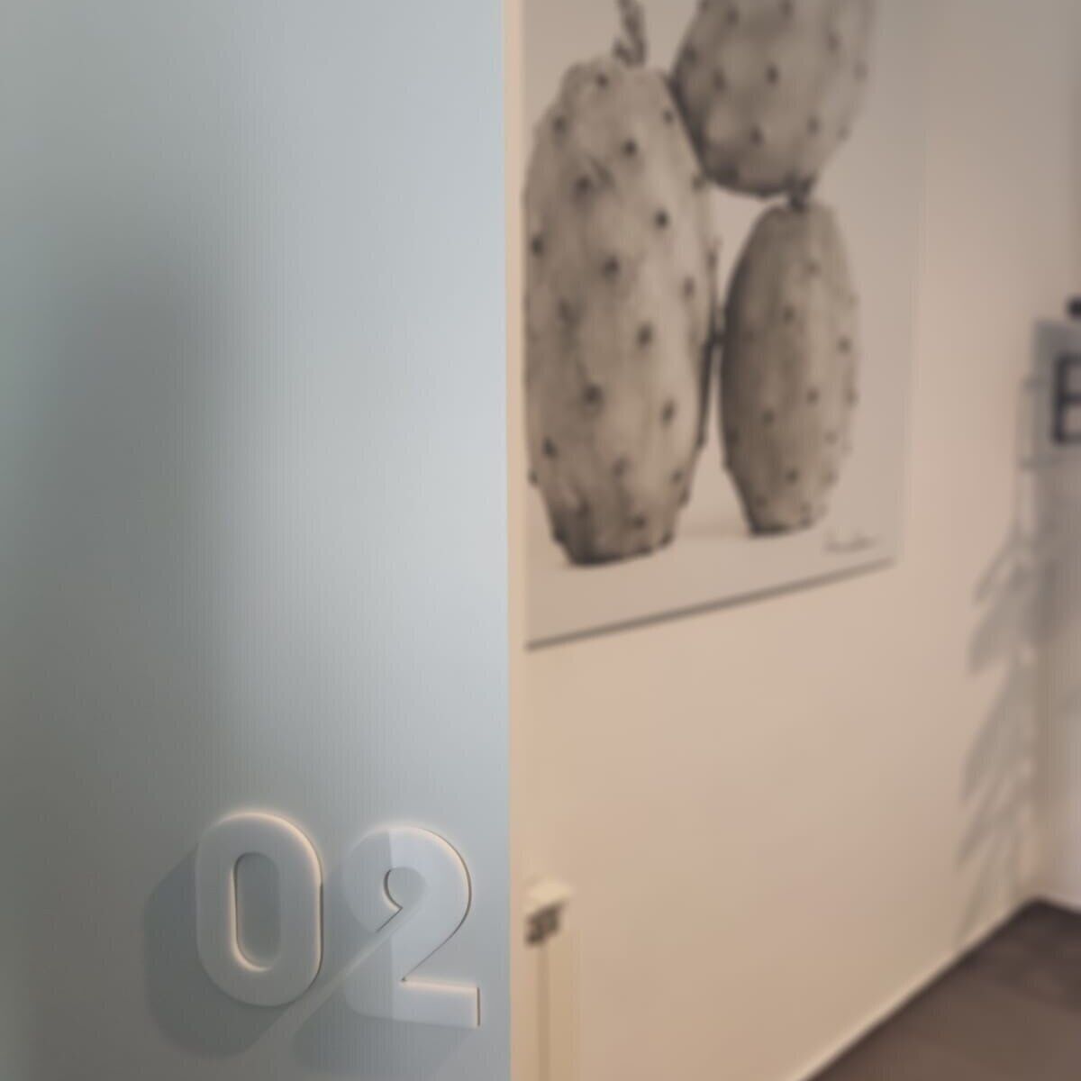 A wall with a number '02' and a framed picture of pears.