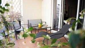 Un balcon avec une table, des chaises et un pot de fleurs.