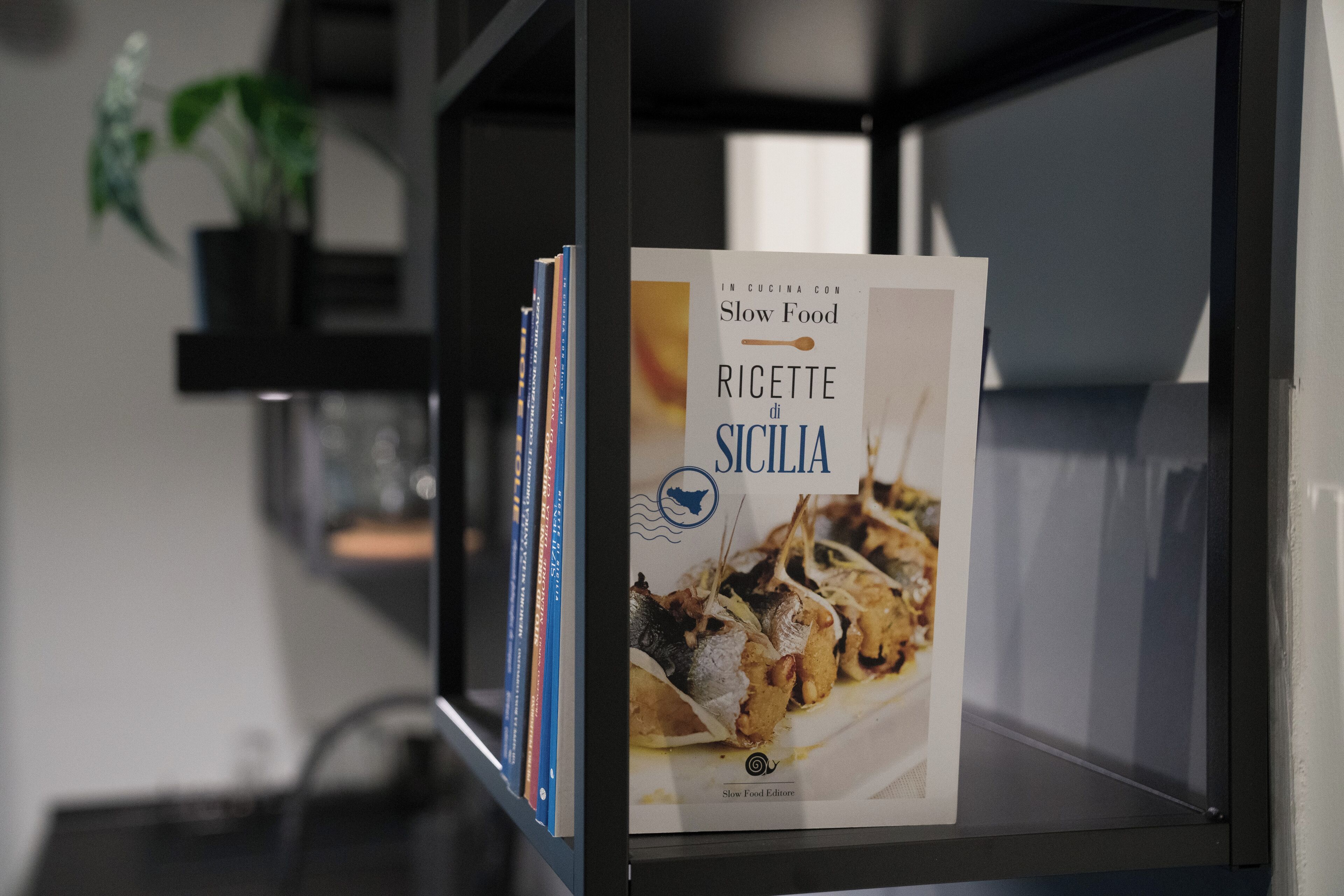 Un livre intitulé « Slow Food Ricette di Sicilia » est posé sur une étagère.