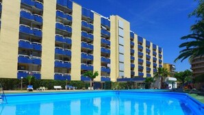 Un hôtel doté d’une piscine, de nombreux balcons et offrant une vue sur un ciel d’un bleu éclatant.