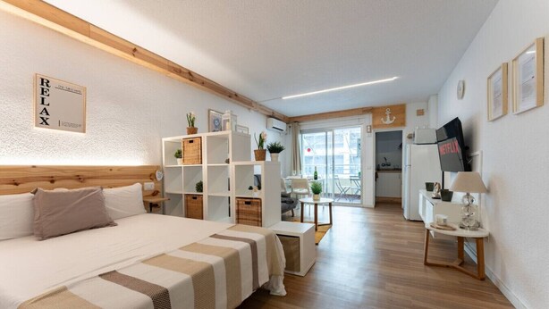 Une chambre d’hôtel moderne dotée d’un grand lit, d’un petit coin repas, d’une kitchenette et d’un balcon avec vue.