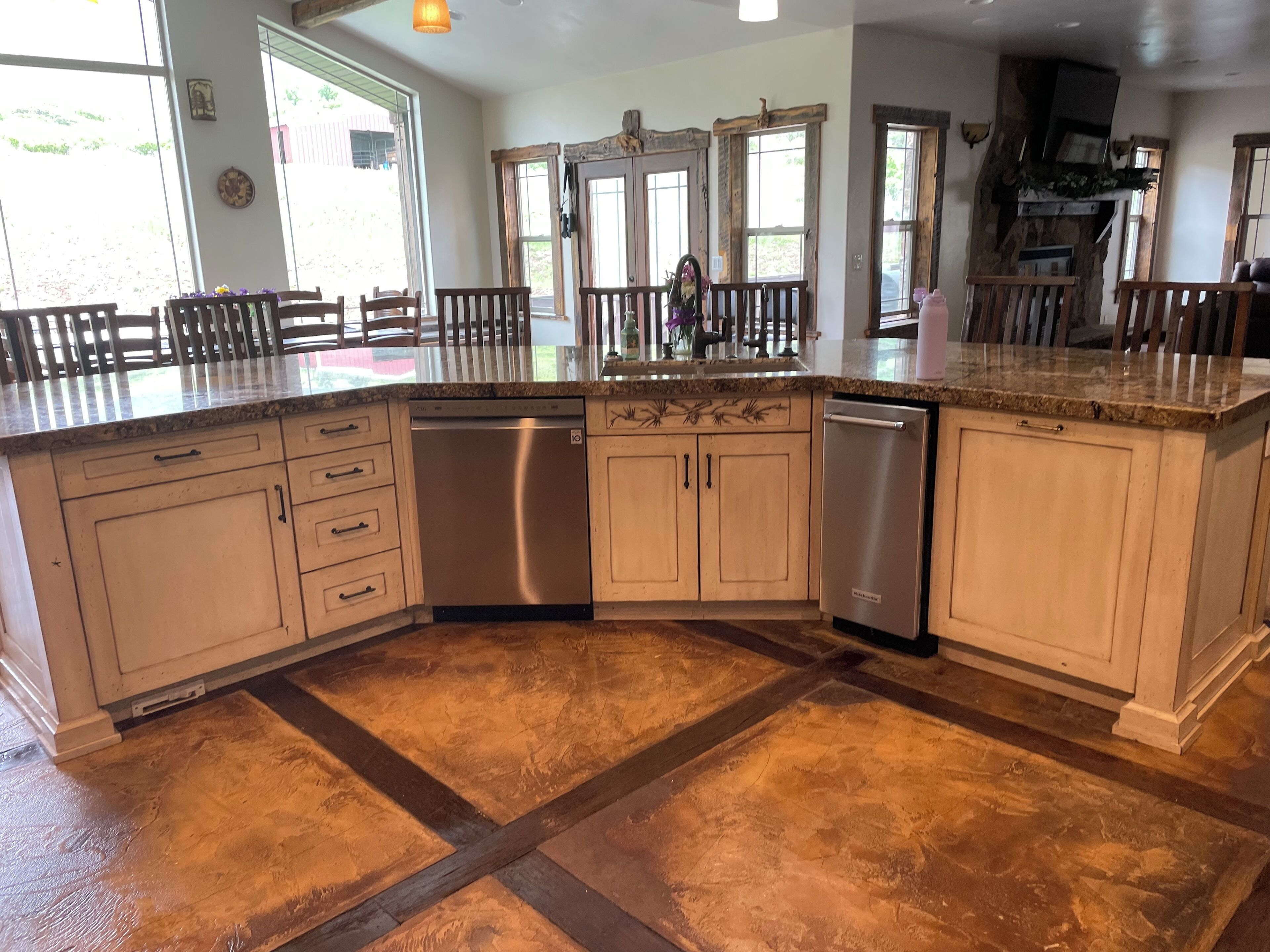 A spacious kitchen with a large island, built-in appliances, and a rustic stone floor.