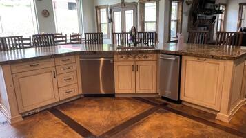 A spacious kitchen with a large island, built-in appliances, and a rustic stone floor.