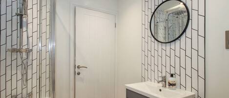 A bathroom with a shower, a toilet, a sink, and a mirror.
