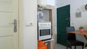 Cocina compacta con estufa, cafetera y cilindro de gas.