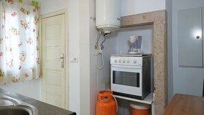 Una cocina con estufa a gas, calentador de agua y pileta.