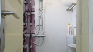 Un baño con ducha, inodoro y cortina.
