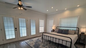 A bedroom with a bed, a ceiling fan, and a large window with blinds. - Watauga Flats Farm – A Working Farm Stay with Rustic Charm & Modern Comfort! (Johnson City)