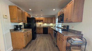 A kitchen with wooden cabinets, a black refrigerator, a coffee maker, and a microwave. - Watauga Flats Farm – A Working Farm Stay with Rustic Charm & Modern Comfort! (Johnson City)