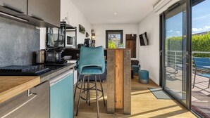 Una cocina moderna con barra, una silla azul y un ventanal corredero que da a un balcón.