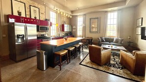 A modern kitchen with a central island, stainless steel appliances, and a dining area with a sofa and chairs. - Brick Haven, 2 bedroom condo in the Grand Traverse Commons (Traverse City)