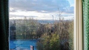 Une vue à travers une fenêtre, avec un panneau indiquant une limitation de vitesse à 30, une rue et des arbres.