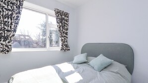 A bedroom with a bed, a window with curtains, and a view of trees outside. - 38 Clive Avenue (Lytham St. Anne's)
