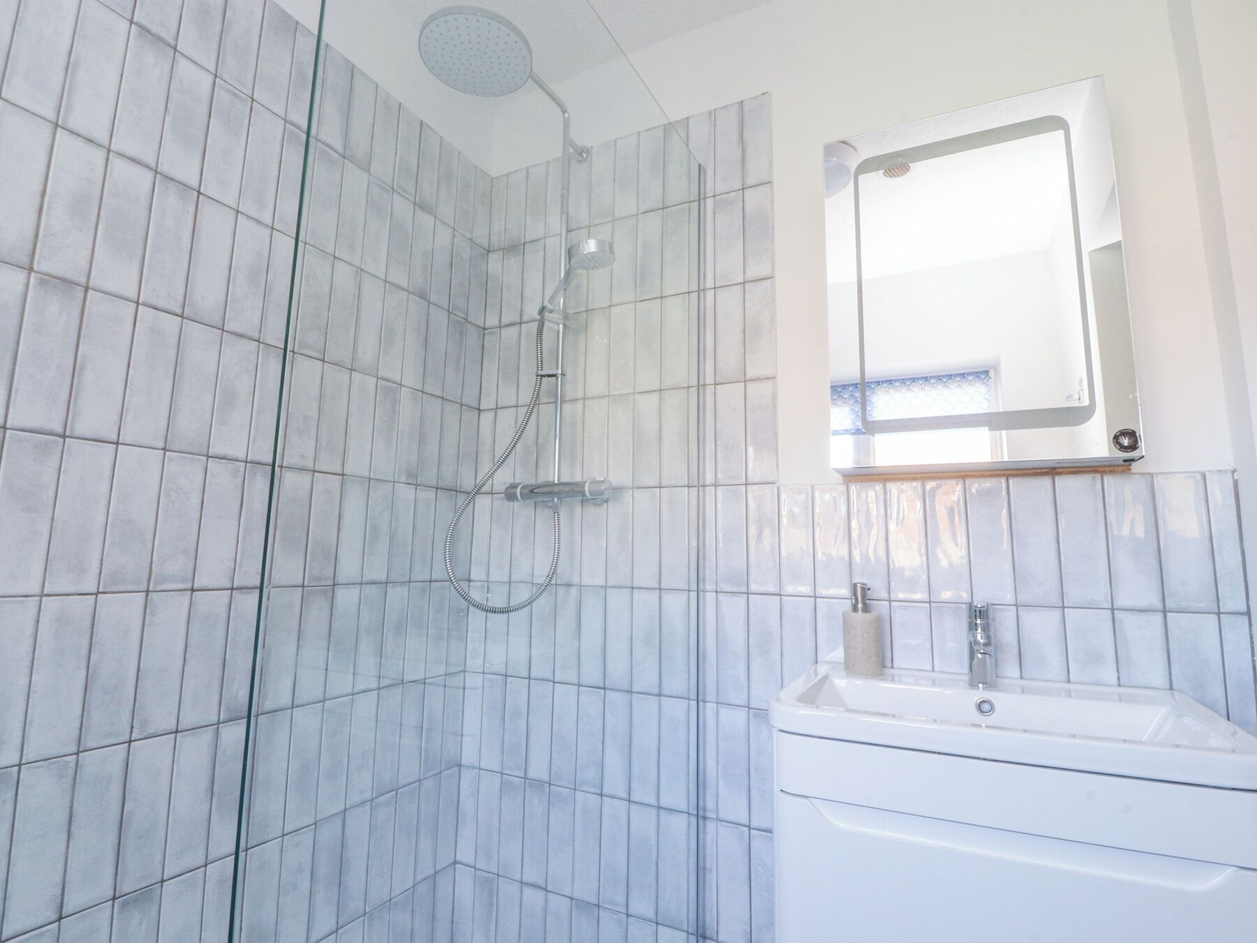 A bathroom with a shower, a sink, and a mirror.