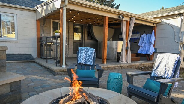 Une terrasse extérieure dotée d’un foyer, de sièges et d’un espace abrité où du linge est suspendu.