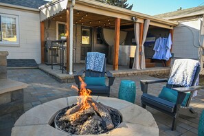 An outdoor patio with a fire pit, seating, and a covered area with clothes hanging. - Central Charming Oasis | Anschutz Medical Campus (Denver)