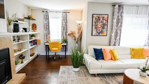 Un salon comprenant un canapé, une table basse, un téléviseur, une bibliothèque et un coin repas avec une chaise.