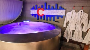 Un hammam doté d’un grand bain à remous, de bancs en bois et de peignoirs blancs suspendus à un porte-manteaux.