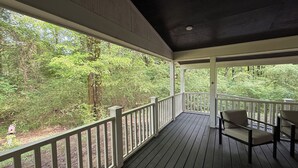 A covered porch with a view of a forest.