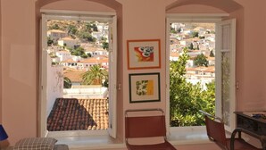 Ένα δωμάτιο με θέα σε μια πόλη που είναι χτισμένη σε έναν λόφο, όπως φαίνεται μέσα από μια ανοιχτή πόρτα.