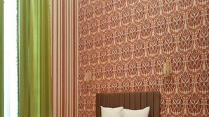 Een slaapkamer met een houten bed, groene gordijnen en behang met een patroon.