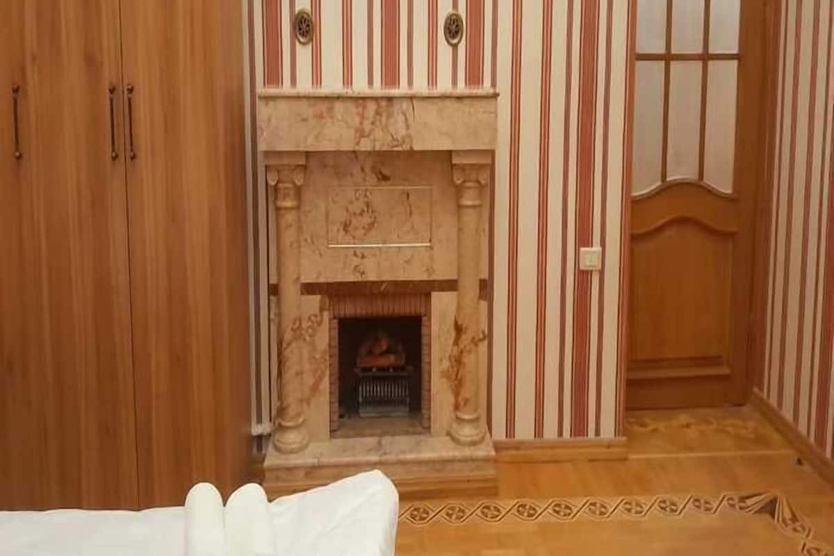 Ein Hotelzimmer mit einem Holzschrank, einem Marmor-Kamin, gestreifter Tapete und Holzboden.
