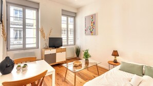 Ein modernes Wohnzimmer mit einem Glastisch, einer Couch, einem Fernseher und einem Essbereich mit Tisch und Stühlen.