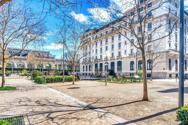 Un amplio patio con un camino empedrado, rodeado de árboles y edificios de arquitectura clásica.