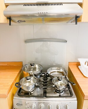 Enjoy cooking in this well-equipped kitchen with a stainless steel stove, pots on the burners, and a range hood with a vent.