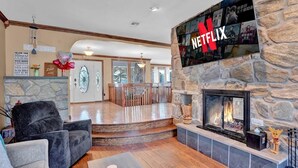 Una sala de estar acogedora con chimenea de piedra, un televisor de pantalla plana en la pared y un espacio de estar cómodo.