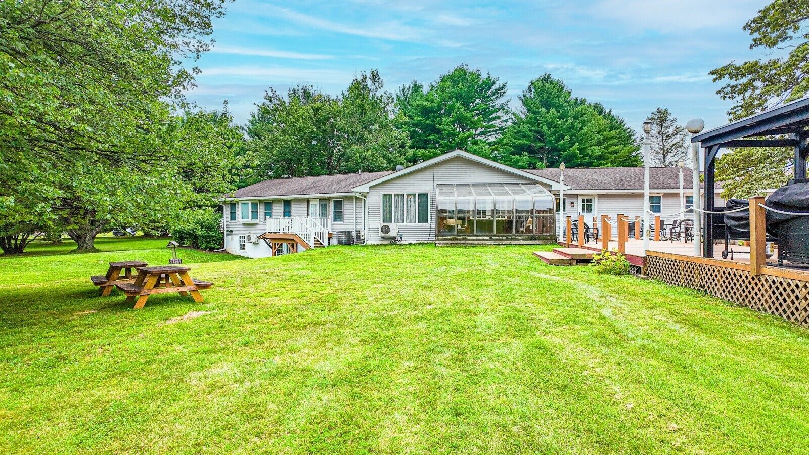 A house with a large front yard, a covered patio, and a picnic table.