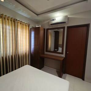 A bedroom with a bed, a wardrobe, a mirror, and an air conditioning unit. - Smart Home Service Apart by Stayz Royale (Chennai)