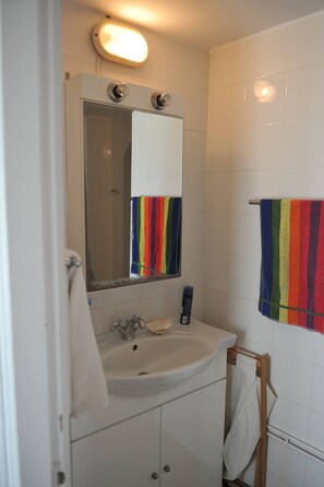 A bathroom with a white sink, a mirror, and a towel rack. - Dione House by GHH (Idra)