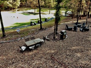 Un área de picnic con una mesa y sillas, rodeada de árboles y un sendero de grava.