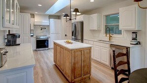 Una cocina moderna con armarios blancos, una isla central y un tragaluz.