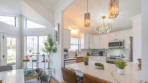 Una cocina moderna con armarios blancos, una isla grande y un comedor con sillas.
