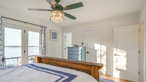 Un dormitorio con una cama, ventilador de techo, cómoda y vista al exterior.