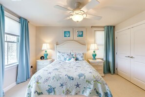 A bedroom with a bed, two bedside tables with lamps, a ceiling fan, and two framed pictures on the wall. - Swim, Hike & Chill: Spacious Ocean View Townhome! (Ocean View)