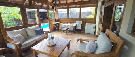 Relax by the pool in this serene outdoor space, featuring comfortable seating and a ceiling fan for a refreshing atmosphere.