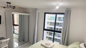 Une chambre d’hôtel avec un lit, une chaise, une fenêtre avec des rideaux et une vue sur un immeuble.