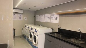Une buanderie équipée de quatre machines à laver, d’un évier et de panneaux d’affichage contenant des informations.