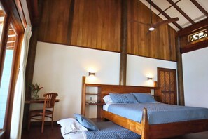Un dormitorio con estructura de madera, una cama, mesitas de noche y una silla.